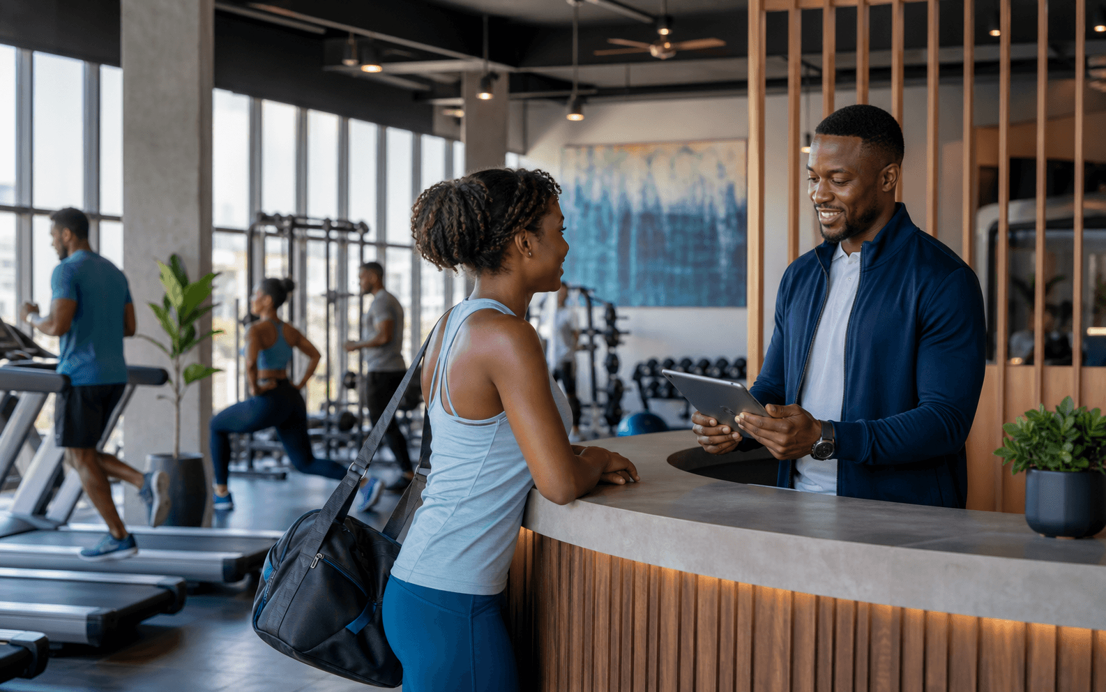 A gym manager using a tablet to welcome and check in a member